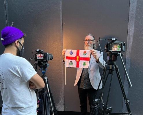Guy Rogers holding a flag in front of a camera