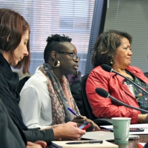 3 women at a desk with microphones and notebooks